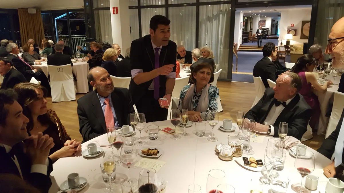 Mago haciendo un juego de cartas en una mesa redonda a la hora del café en una cena de empresa