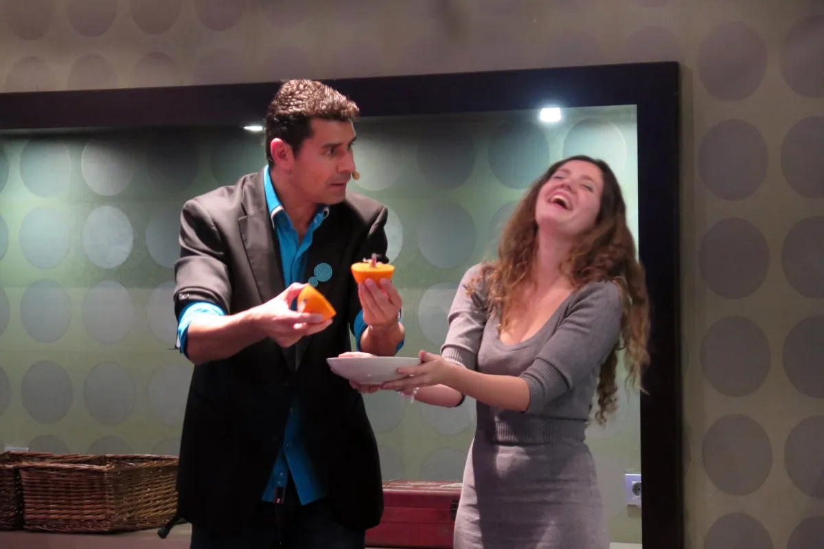 Mago con una voluntaria que se ríe a carcajadas en el escenario durante una cena de empresa