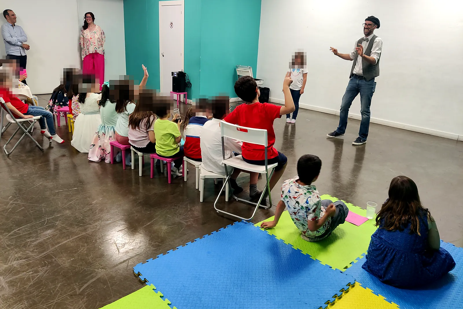 Una niña de pie junto al mago, delante de sus amigos sentados, durante un espectáculo de magia de cumpleaños