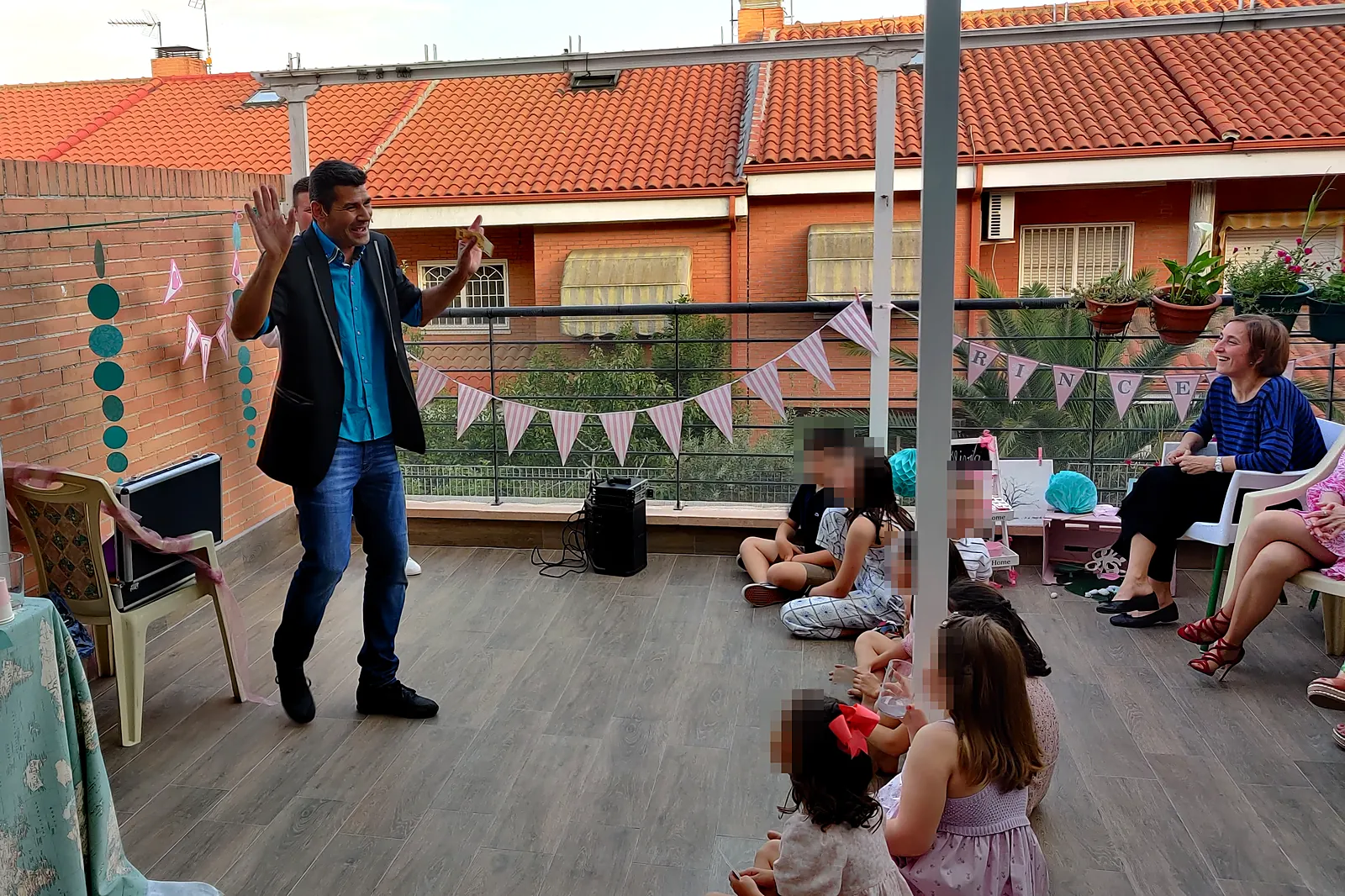 Mago actuando en una terraza ante niños sentados en el suelo y algunos adultos que miran el espectáculo