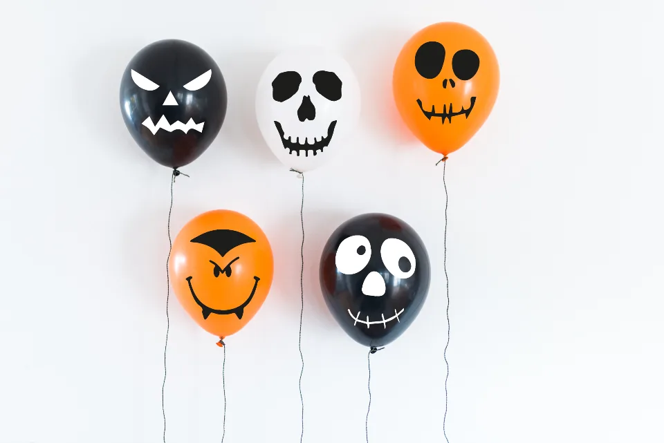Globos negros, blancos y naranjas con caras de Halloween dibujadas